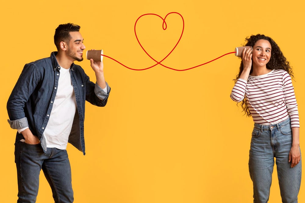couple talking on cup phone with a heart shape in the phone cord