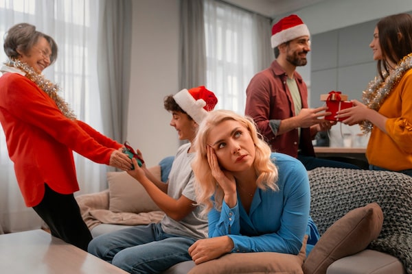 family celebrating christmas with woman in foreground looking fed up