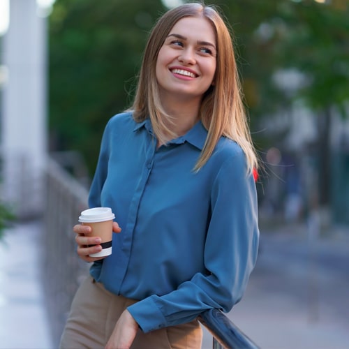 woman outdoors with coffee smiling