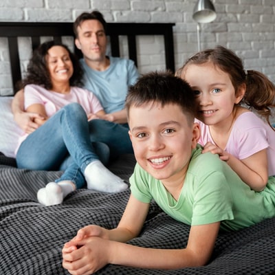 young family sitting on bed together smiling