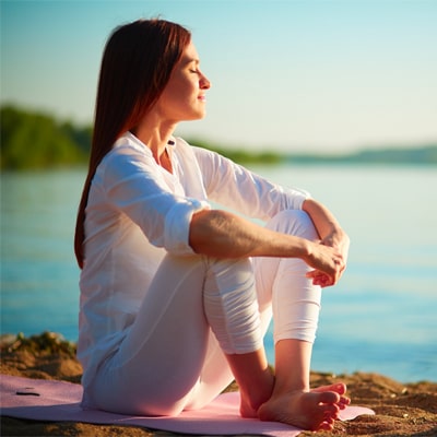 woman meditating calmly by lake