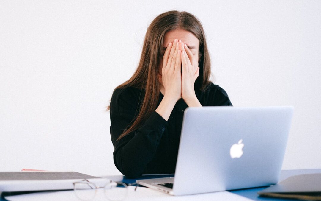 Woman With Hands on her Face in front of a Laptop