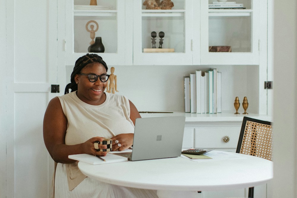 woman using laptop at kitchen table smiling