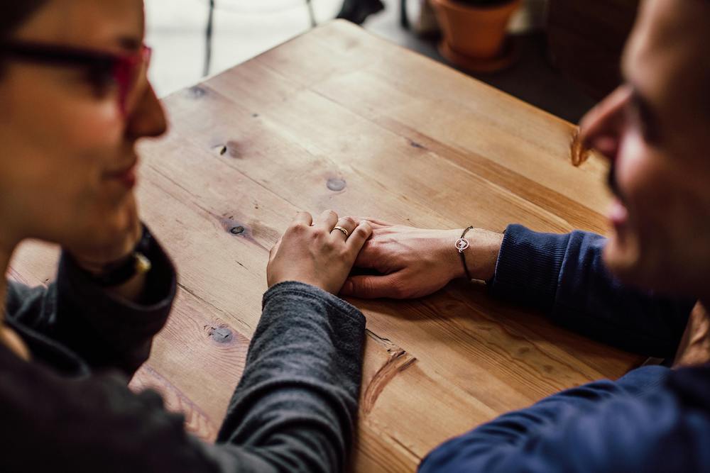 woman holding man's hand supportively