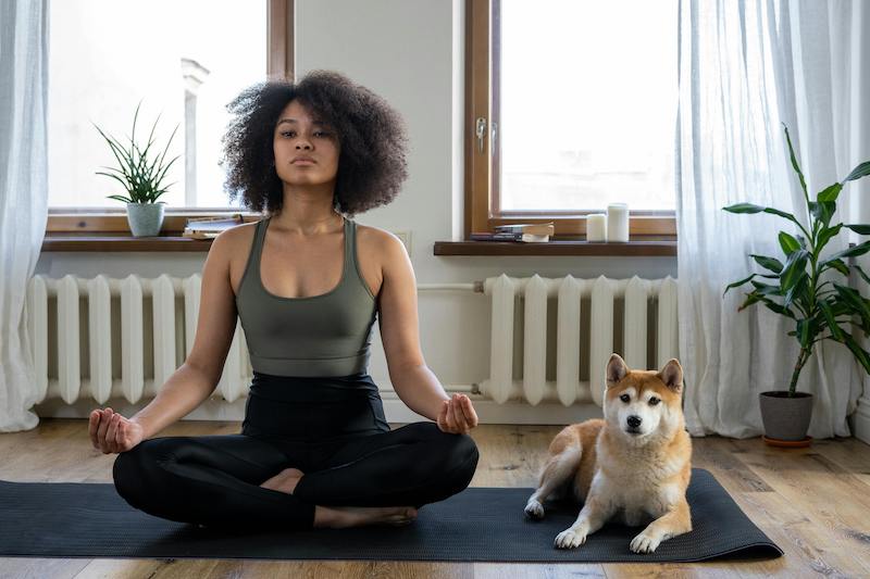 woman doing yoga next to dog