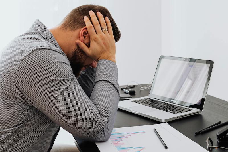 man with head in hands at work desk