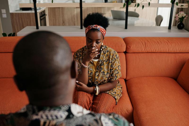 woman sitting opposite man on sofa and talking