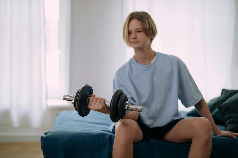 teenager on bed lifting weight