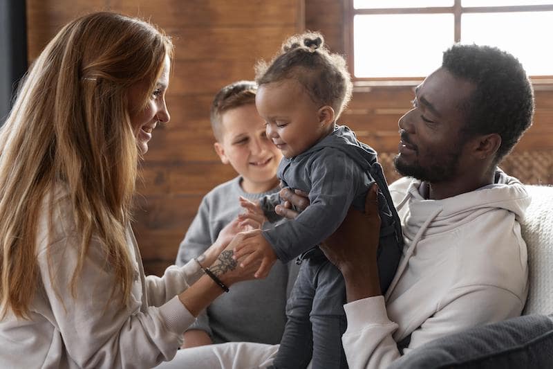 father holding son facing smiling mother