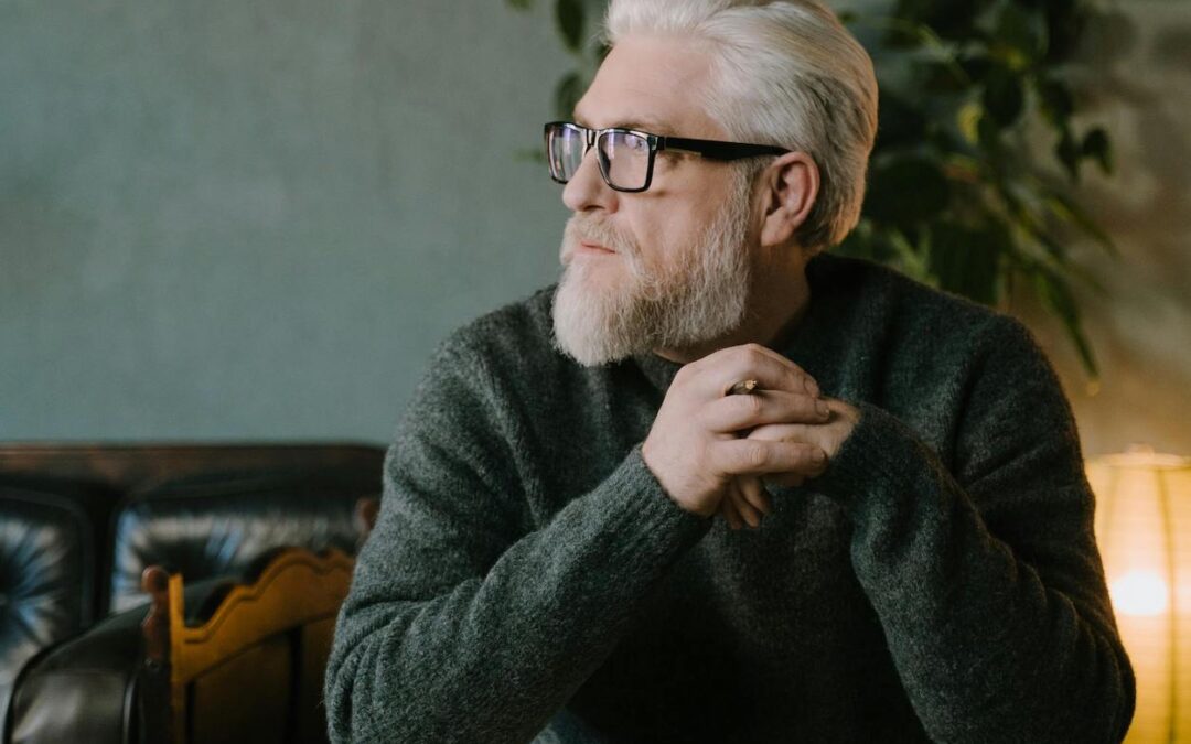 man sitting at desk with pen in hand contemplating