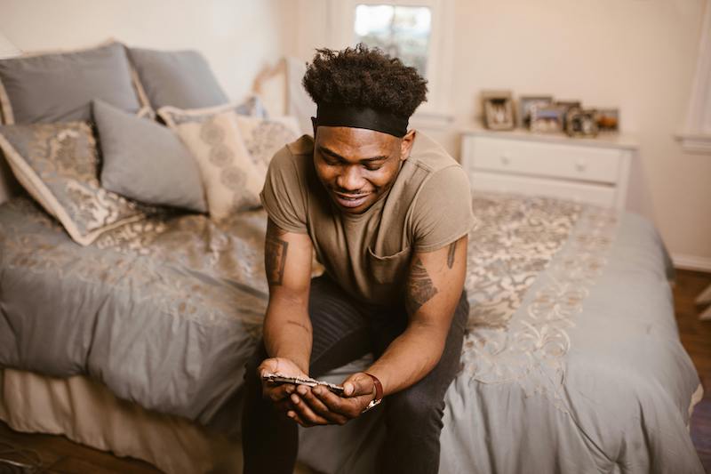 man sitting on bed smiling at photo