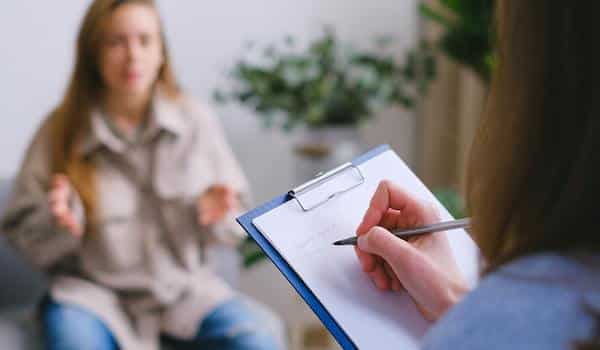 an talking to therapist making notes on clipboard